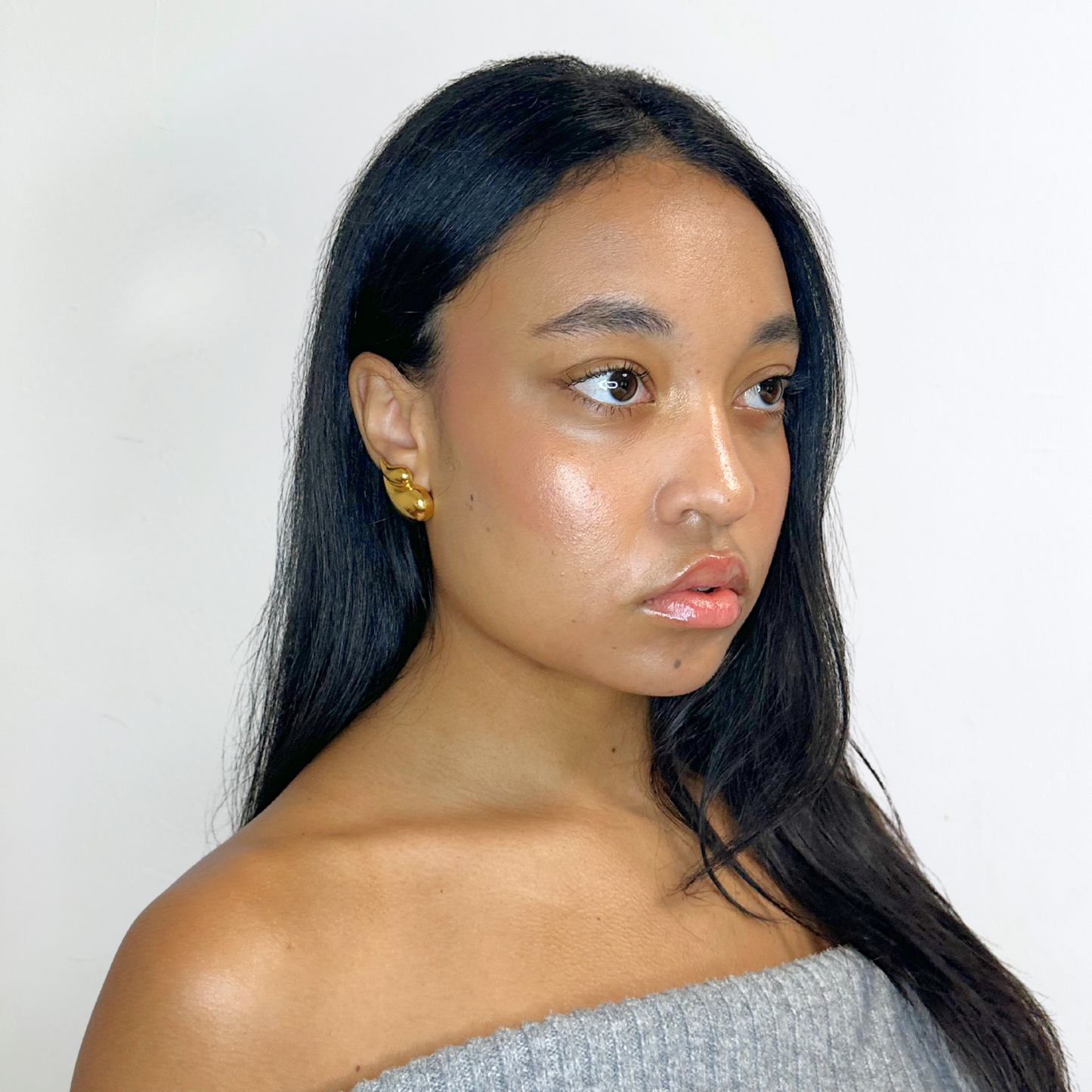 Close-up of woman wearing Alvéra Gold Fluid Drop Stud Earrings – elegant gold-plated studs, refined minimalist jewelry for women