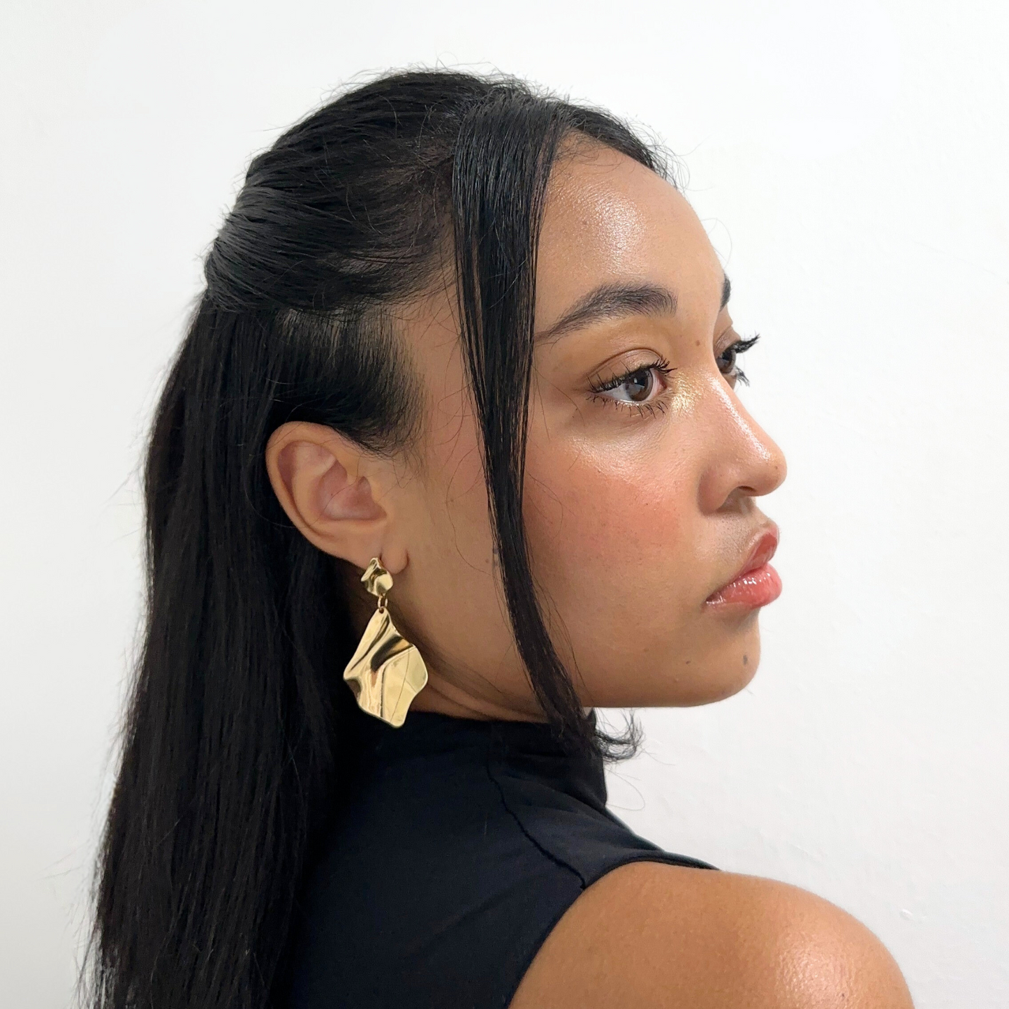Side profile of woman wearing Alvéra Gold Wavy Drop Earrings – elegant gold-plated drop earrings, classy and trendy jewelry style